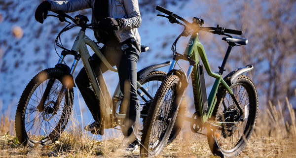 Rider on a silver Magnum Peak with a green Peak parked next to it on mountain trail